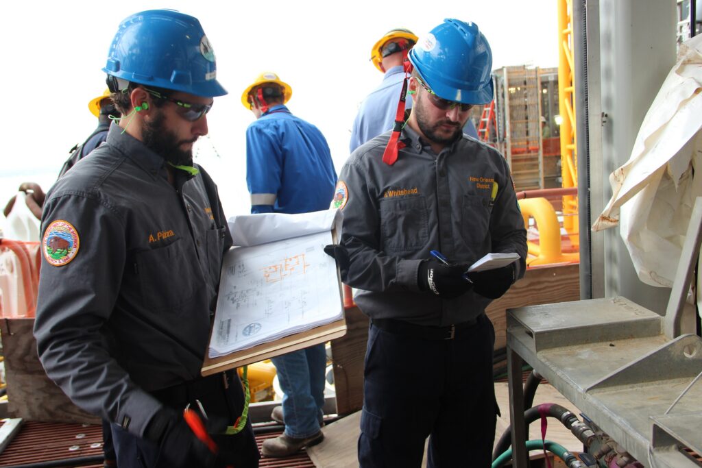 Inspector in a hard hat reviewing documents on an offshore platform