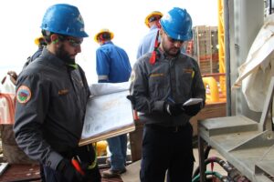 Inspector in a hard hat reviewing documents on an offshore platform