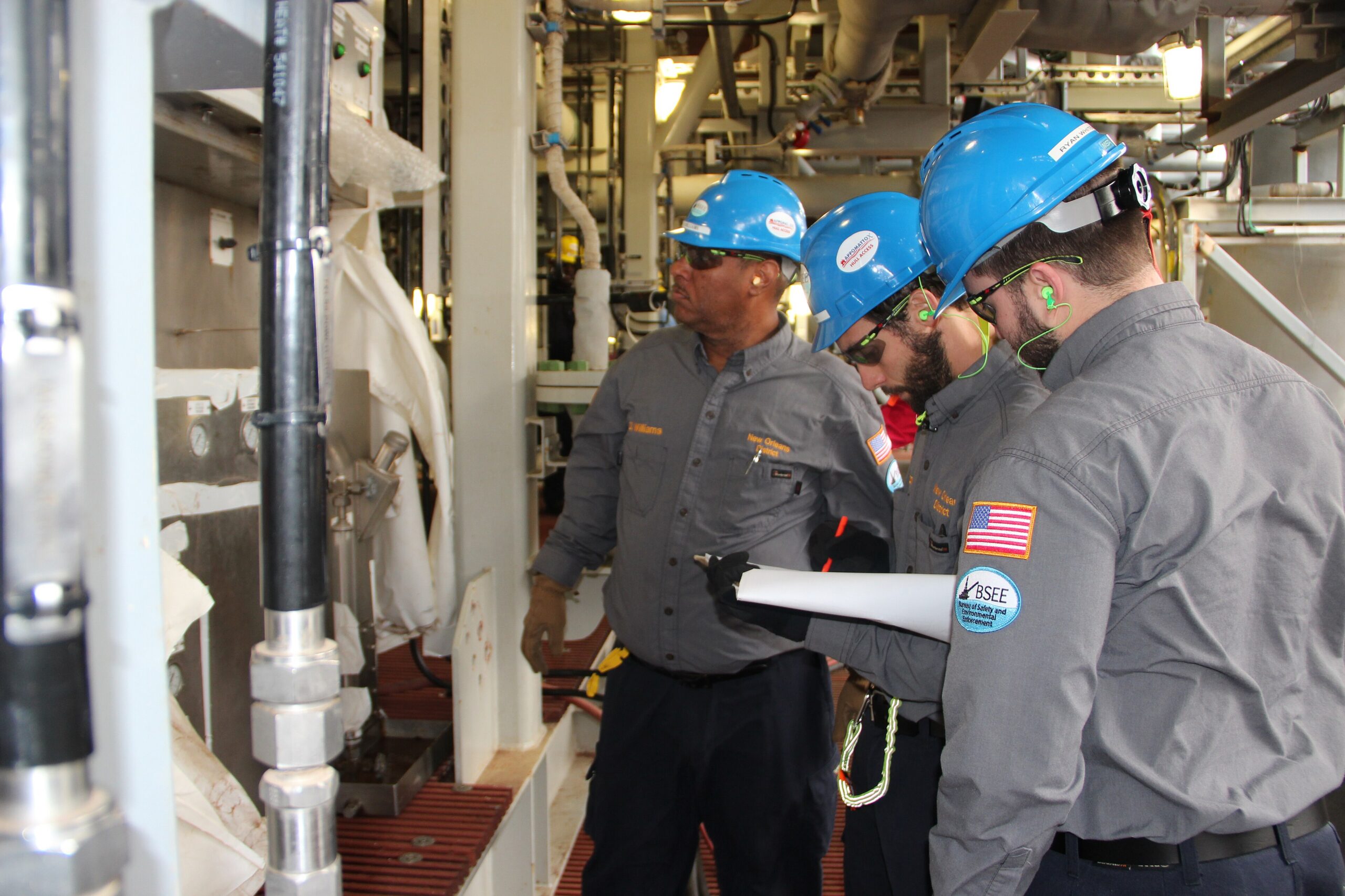 Inspectors in hard hats discussing records with a clipboard on site