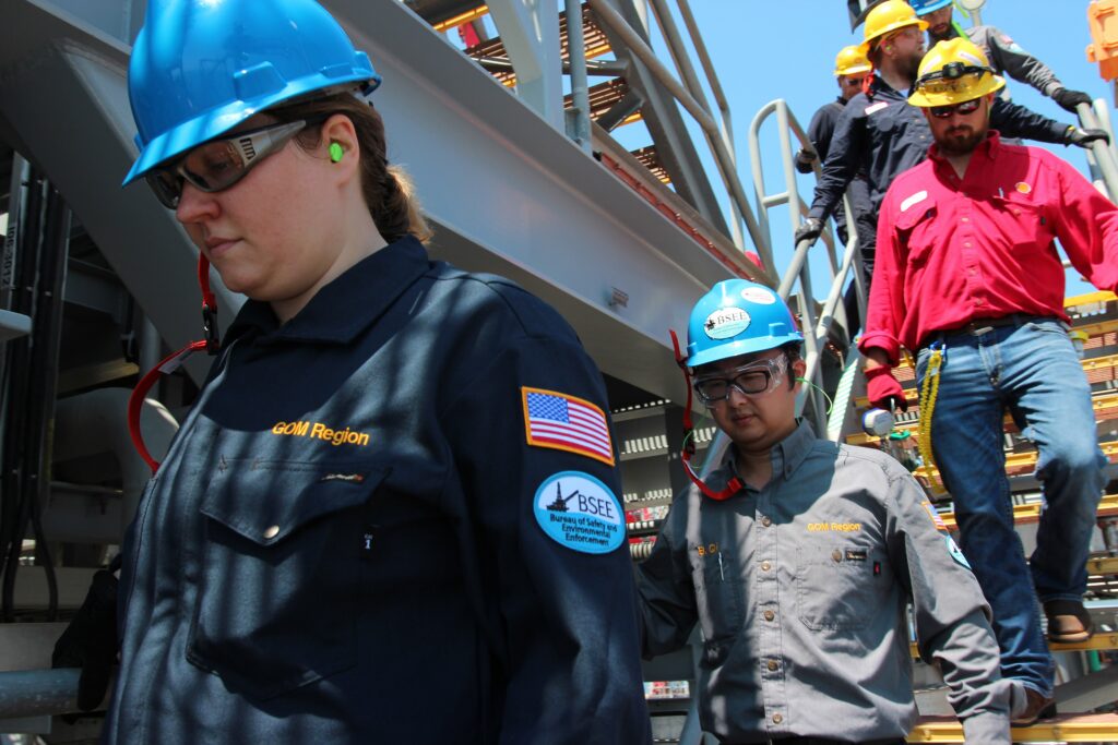 Workers in hard hats and safety glasses on an industrial platform