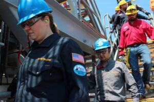 Workers in hard hats and safety glasses on an industrial platform