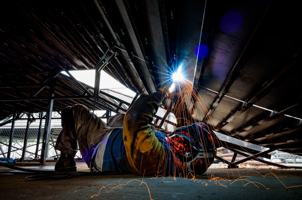 Welder working under a steel structure with sparks